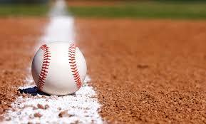 A baseball lies on the ground of a baseball field.